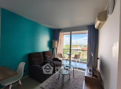 Cozy living room with balcony view, featuring modern furniture and vibrant blue accent wall.