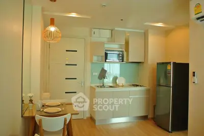 Modern kitchen with dining area, featuring sleek cabinetry and stainless steel appliances.