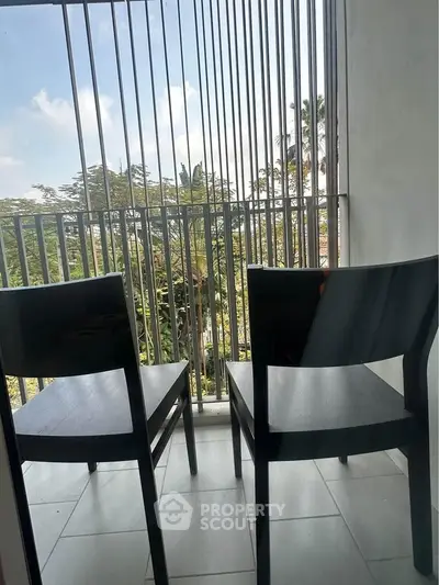 Charming balcony with two chairs offering a serene view of lush greenery, perfect for relaxation.