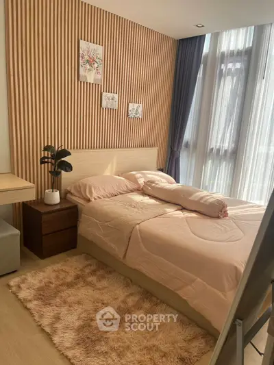 Cozy bedroom with modern decor and natural light, featuring a plush rug and stylish wall art.