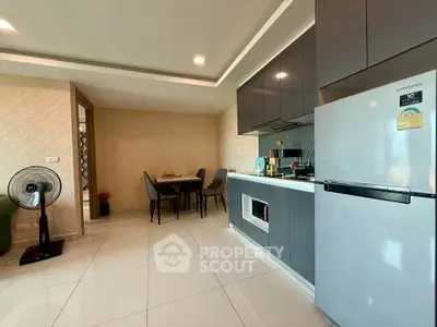 Modern kitchen with sleek cabinetry and dining area in open layout apartment.