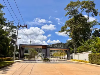 Elegant gated entrance of a modern residential community with lush greenery and clear blue sky.