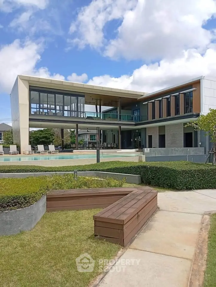 Modern luxury home with expansive glass windows and lush landscaping