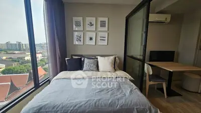 Modern bedroom with large window and city view, featuring stylish decor and cozy workspace.