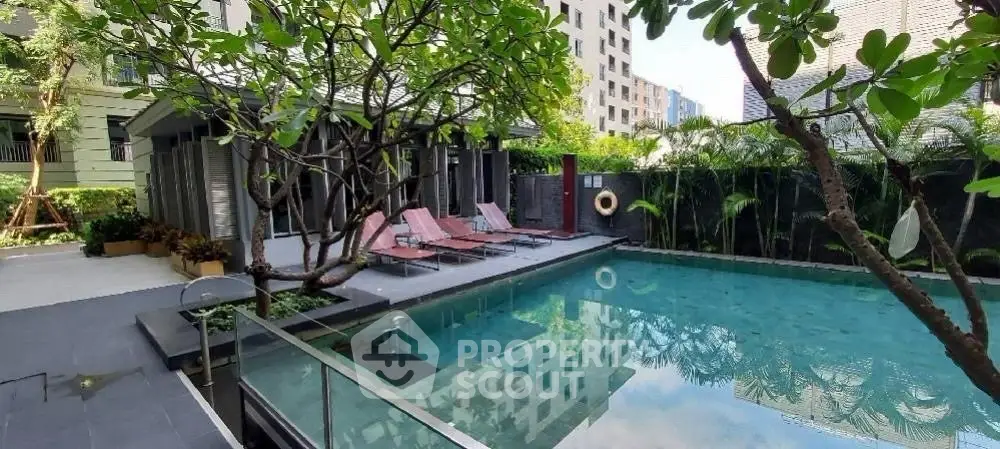 Luxurious residential pool area with sun loungers and lush greenery, perfect for relaxation.
