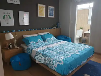 Modern bedroom with stylish decor and ensuite bathroom, featuring vibrant blue bedding and wall art.