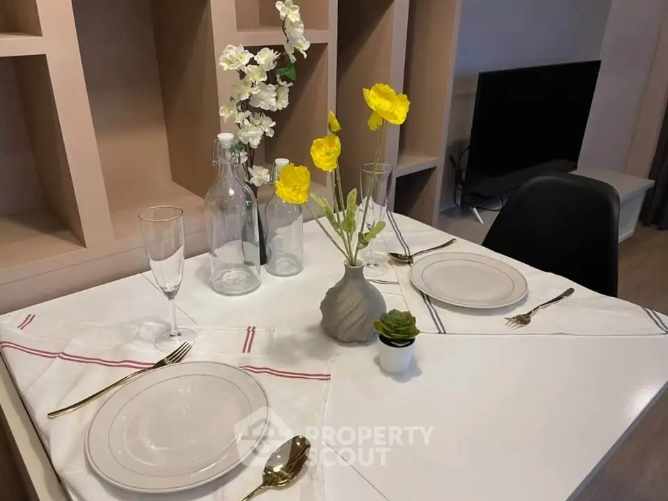 Elegant dining setup with modern decor and vibrant flowers in a stylish apartment.