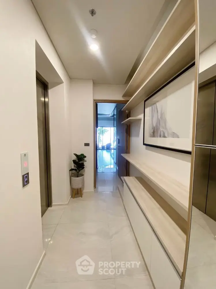 Modern hallway with sleek shelving and elevator access in luxury apartment building.