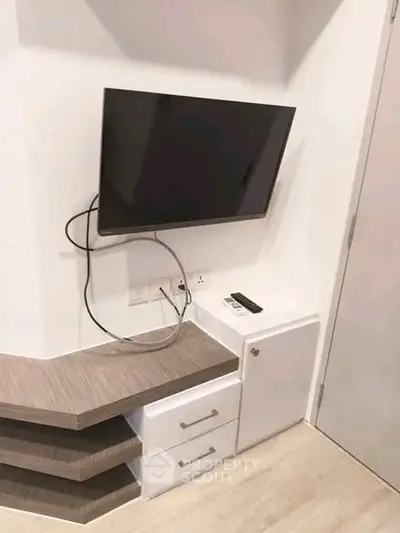 Modern living room corner with mounted TV and sleek storage unit.