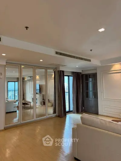 Spacious living room with mirrored wall and balcony access