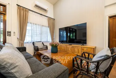 Charming living room with cozy seating and large TV, perfect for relaxation and entertainment.