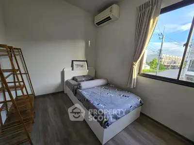 Cozy bedroom with single bed, air conditioning, and large window with street view.