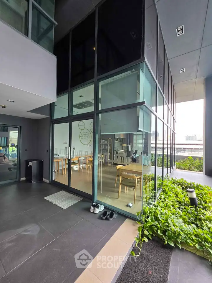 Modern building entrance with glass facade and greenery