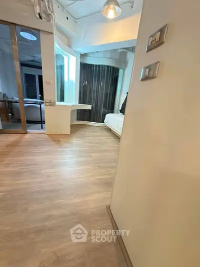 Modern apartment interior with wooden flooring and stylish lighting, featuring a cozy bedroom area.