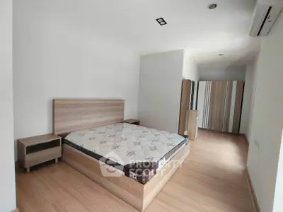 Spacious bedroom with modern wooden furniture and ample natural light.