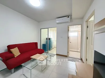 Modern living room with red sofa and glass coffee table, featuring air conditioning.