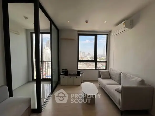 Modern living room with city view, featuring sleek furniture and large windows for natural light.