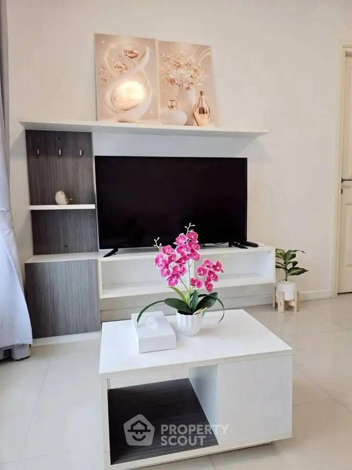 Modern living room with sleek TV stand, elegant decor, and vibrant orchid centerpiece.
