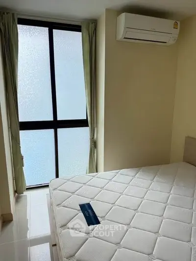 Cozy bedroom with large window and air conditioning unit, perfect for comfortable living.