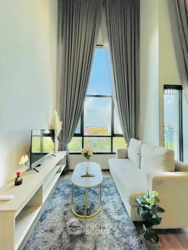 Modern living room with high ceilings, large window, and elegant decor in a stylish apartment.