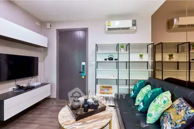 Modern living room with sleek furniture and air conditioning, featuring a stylish TV setup and decorative shelving.