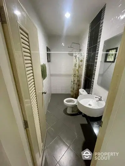 Compact and functional bathroom with white fixtures, tiled flooring, and a shower area, ideal for urban living spaces.