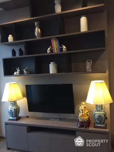 Elegant living room with custom shelving, chic decor, and ambient lighting from stylish table lamps flanking a modern flat-screen TV.