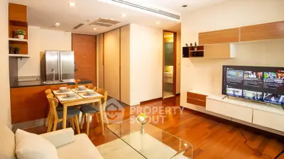 Modern open-plan living room with kitchen and dining area, featuring sleek wooden flooring.