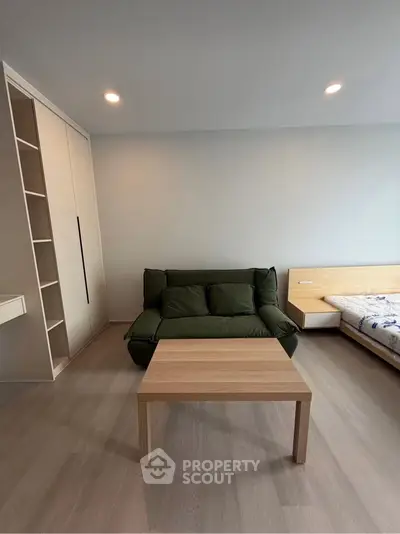 Modern living room with green sofa, wooden table, and built-in storage in a cozy apartment.