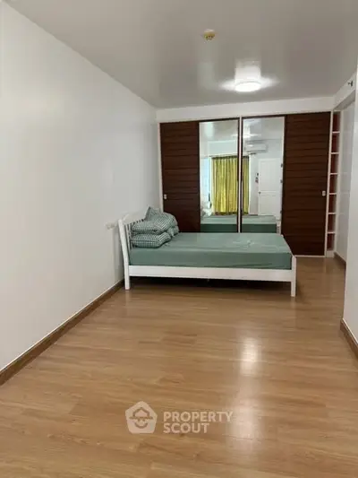 Spacious bedroom with wooden flooring and mirrored closet doors