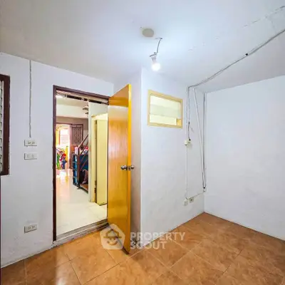 Cozy small room with tiled floor and wooden door, ideal for storage or utility use.