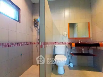 Modern bathroom with shower and stylish sink in a tiled setting.