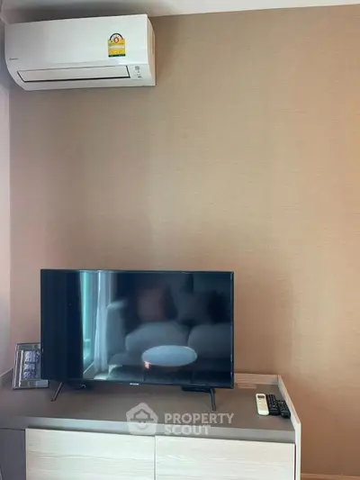 Modern living room with air conditioner and flat-screen TV on a sleek cabinet.