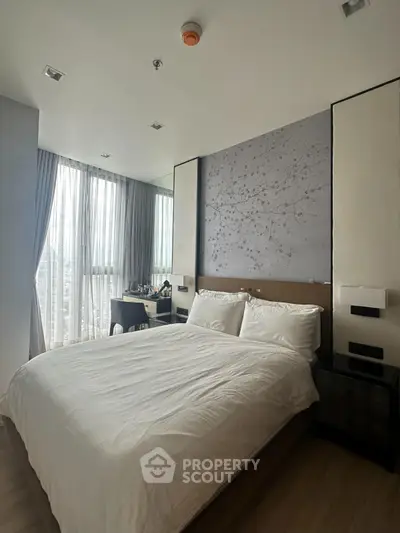 Modern bedroom with large window and elegant decor in high-rise apartment.