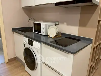 Modern kitchen with sleek appliances including washing machine and microwave, ideal for compact living spaces.