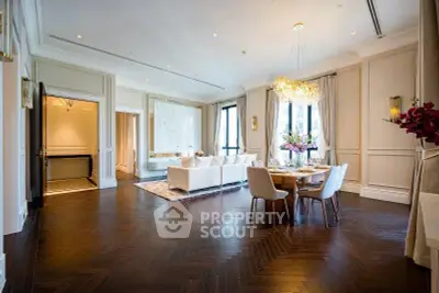 Luxurious open living and dining area with elegant chandelier and hardwood floors