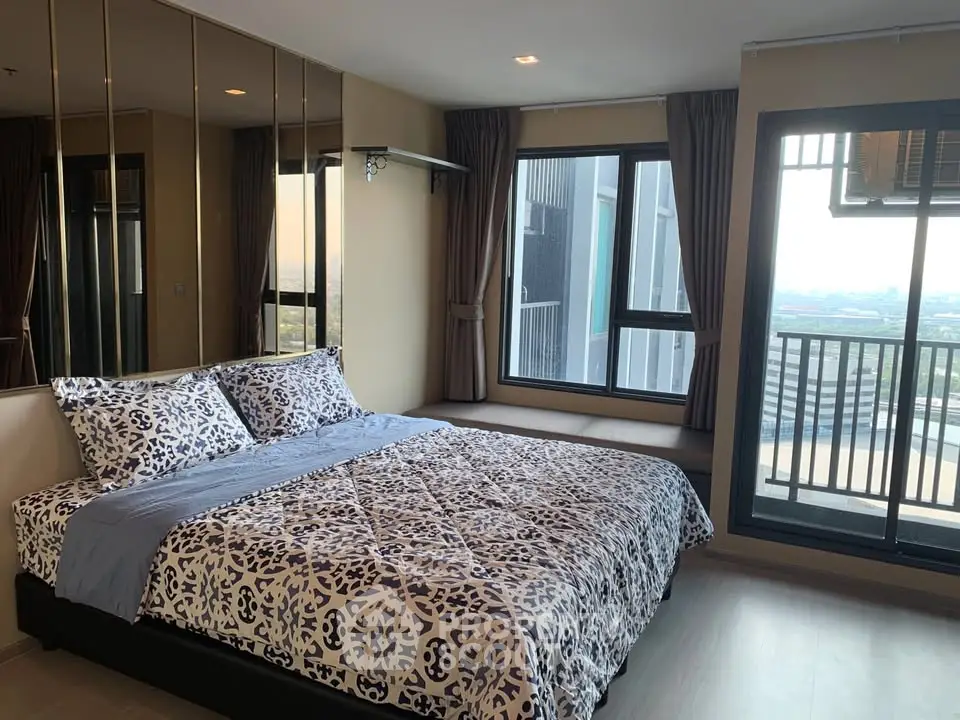 Modern bedroom with large windows and city view, featuring stylish bedding and sleek design.