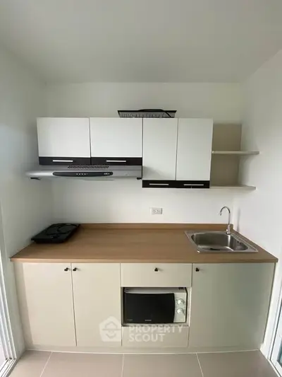 Modern compact kitchen with sleek cabinetry and built-in appliances, ideal for efficient cooking in small spaces.