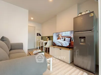Modern living room with cozy sofa, sleek refrigerator, and stylish decor in a contemporary apartment.