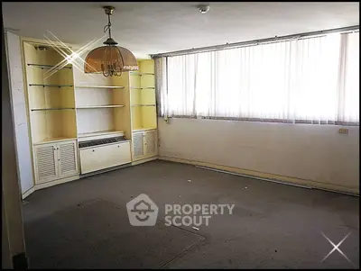 Spacious living room with large windows and built-in shelves, ideal for customization.