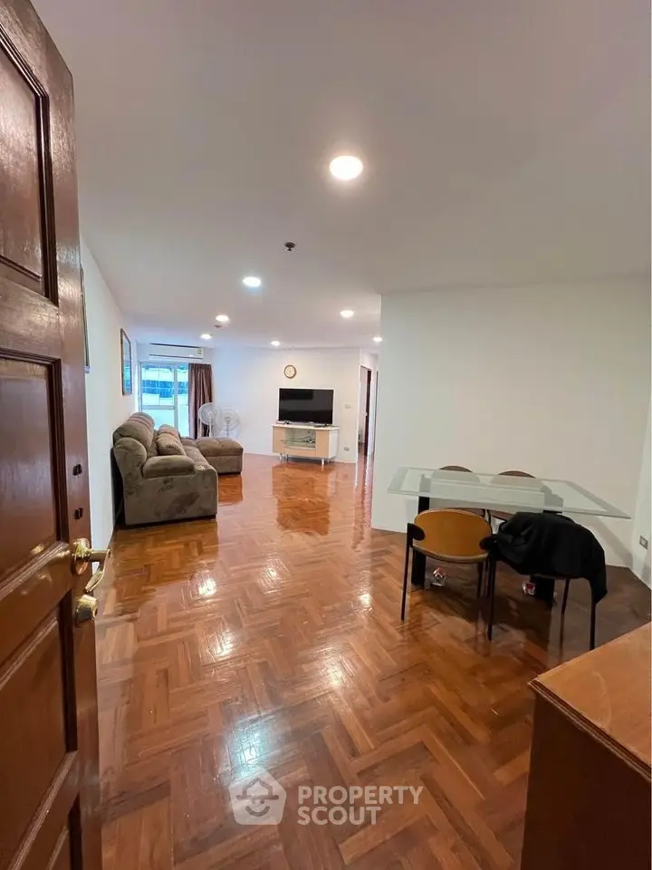 Spacious living room with wooden flooring and modern furniture in a cozy apartment.