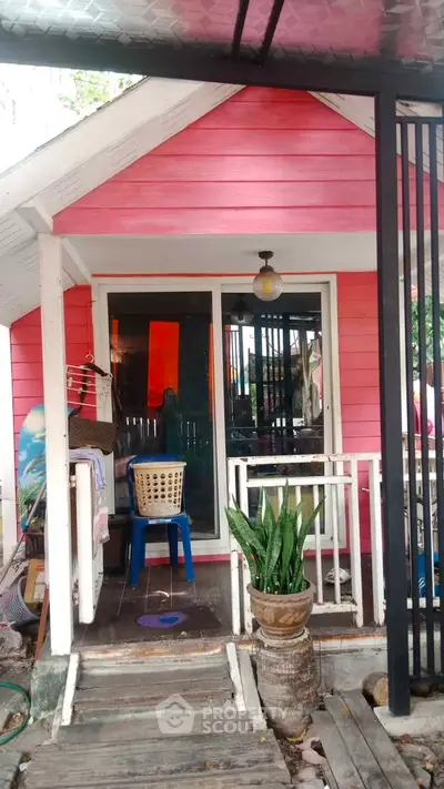 Charming pink tiny house with inviting porch and potted plants