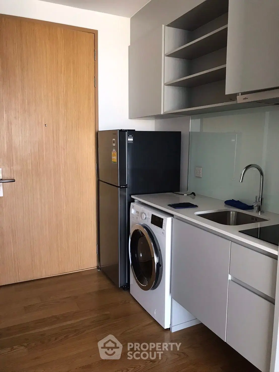 Modern compact kitchen with washing machine and fridge in sleek apartment