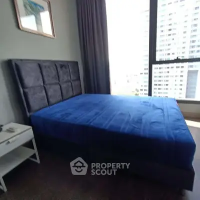 Modern bedroom with large window and blue bedding in high-rise apartment