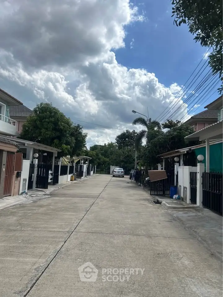 Charming suburban street view with modern houses and lush greenery under a vibrant sky.