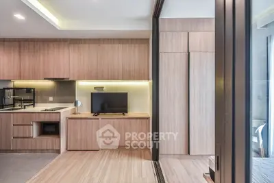 Modern studio apartment with sleek wooden cabinetry and integrated TV unit, showcasing contemporary design.
