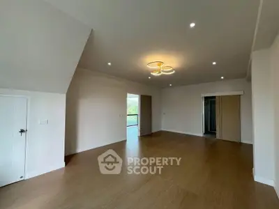 Spacious modern living room with wooden flooring and stylish ceiling lights.