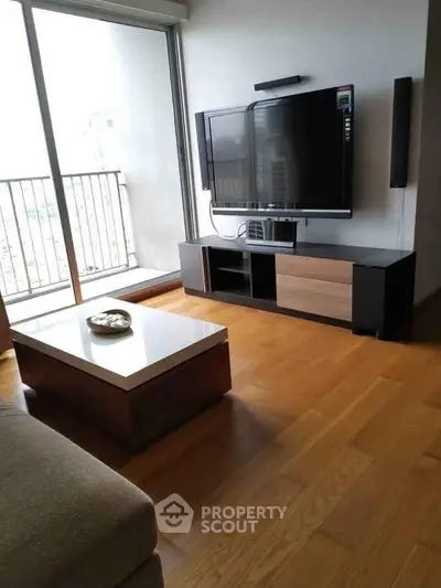 Modern living room with sleek TV setup and large window offering natural light.