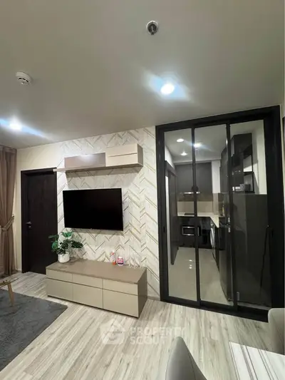 Modern living room with sleek TV unit and glass partition to kitchen