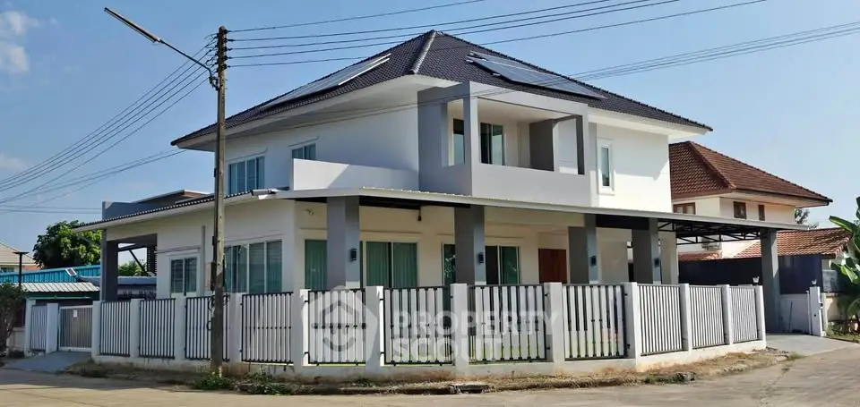 Modern two-story house with white fence and sleek design in suburban neighborhood.